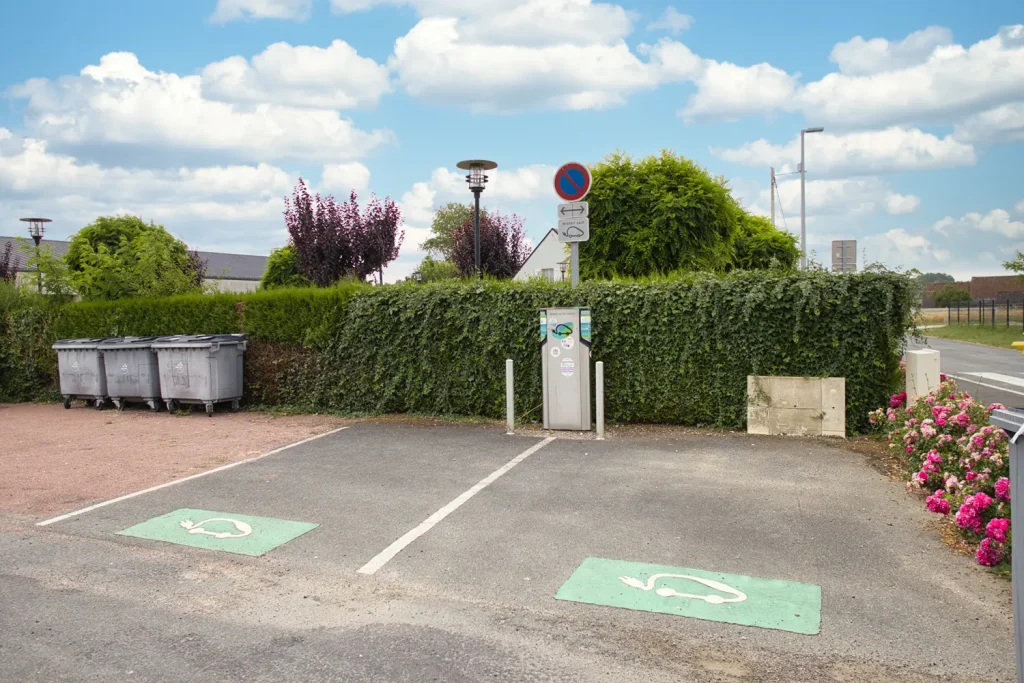 Borne de recharge et deux emplacements pour véhicules électriques sur le parking de la salle des fêtes